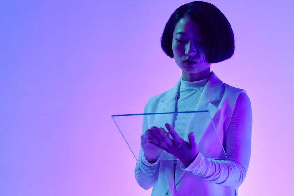Mujer interactuando con una pantalla digital transparente en iluminación vibrante de estudio