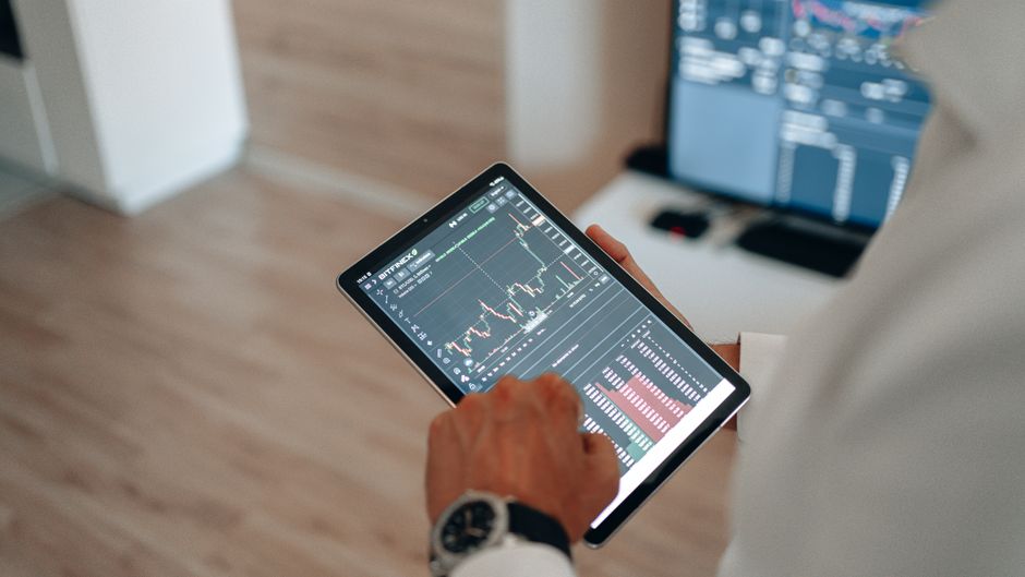 Manos usando una tableta para análisis de mercado y trading en línea